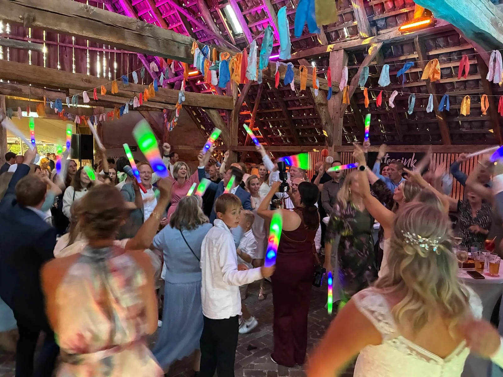 Bruiloftsgasten met lichtstaven op de dansvloer